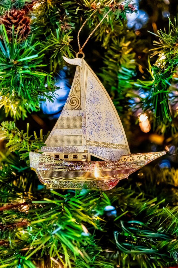 Golden sailboat ornament on a Christmas tree with lights