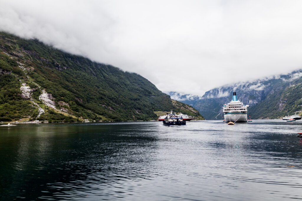 Norwegian alaska cruise ship sailing through Alaska fjord surrounded by scenic mountains and misty skies