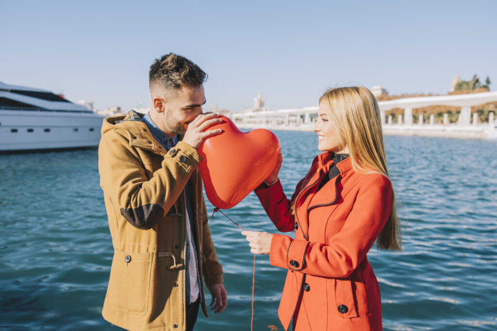 Couple enjoying  best cruise destinations in the world in December 2024 with a date by the water with a heart-shaped balloon