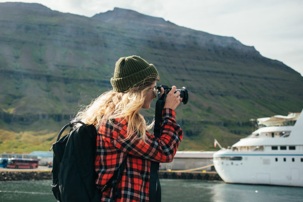 Woman photographing a alaska cruises ship in an Alaskan fjord during peak season