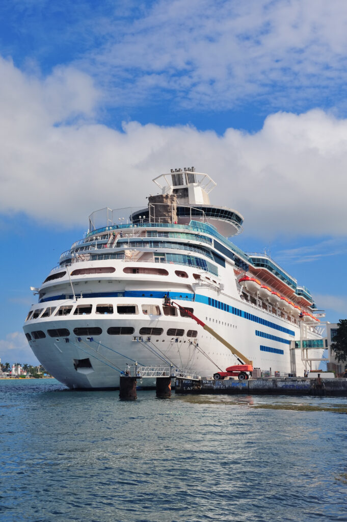 Large cruise ship docked at a port in Miami with a vibrant blue sky and calm waters, ready for an exciting ocean adventure.