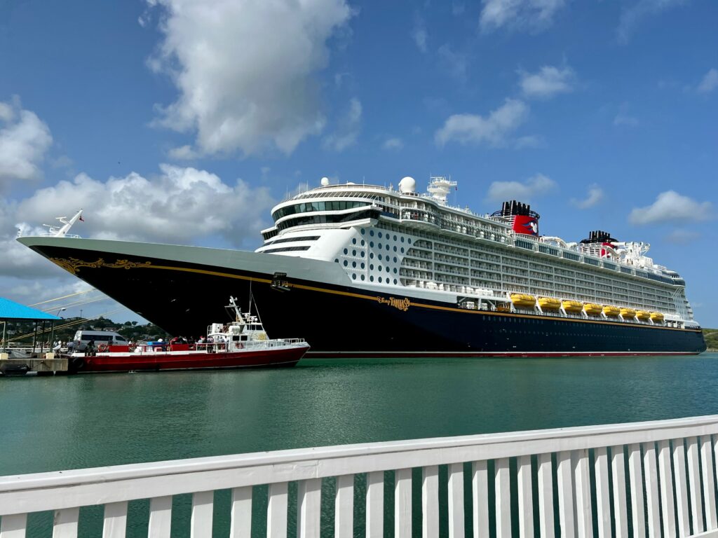 Disney cruise ship docked at a scenic port